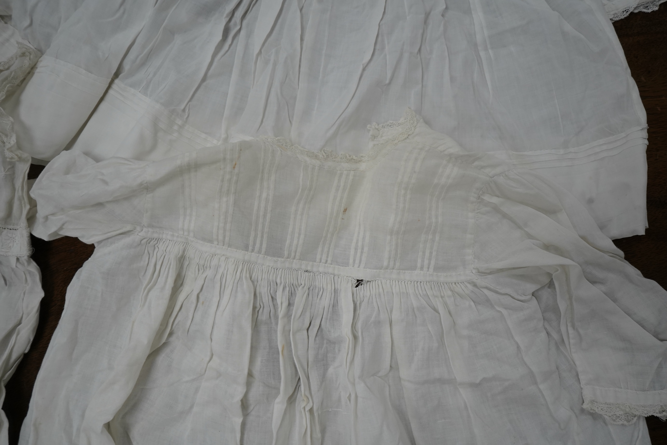 An early 20th century cream silk young girls day dress, together with six similar sized cotton and fine lawn day dresses and a bonnet, all dresses worked with tucking, feather stitching, some lace edged, the bonnet made